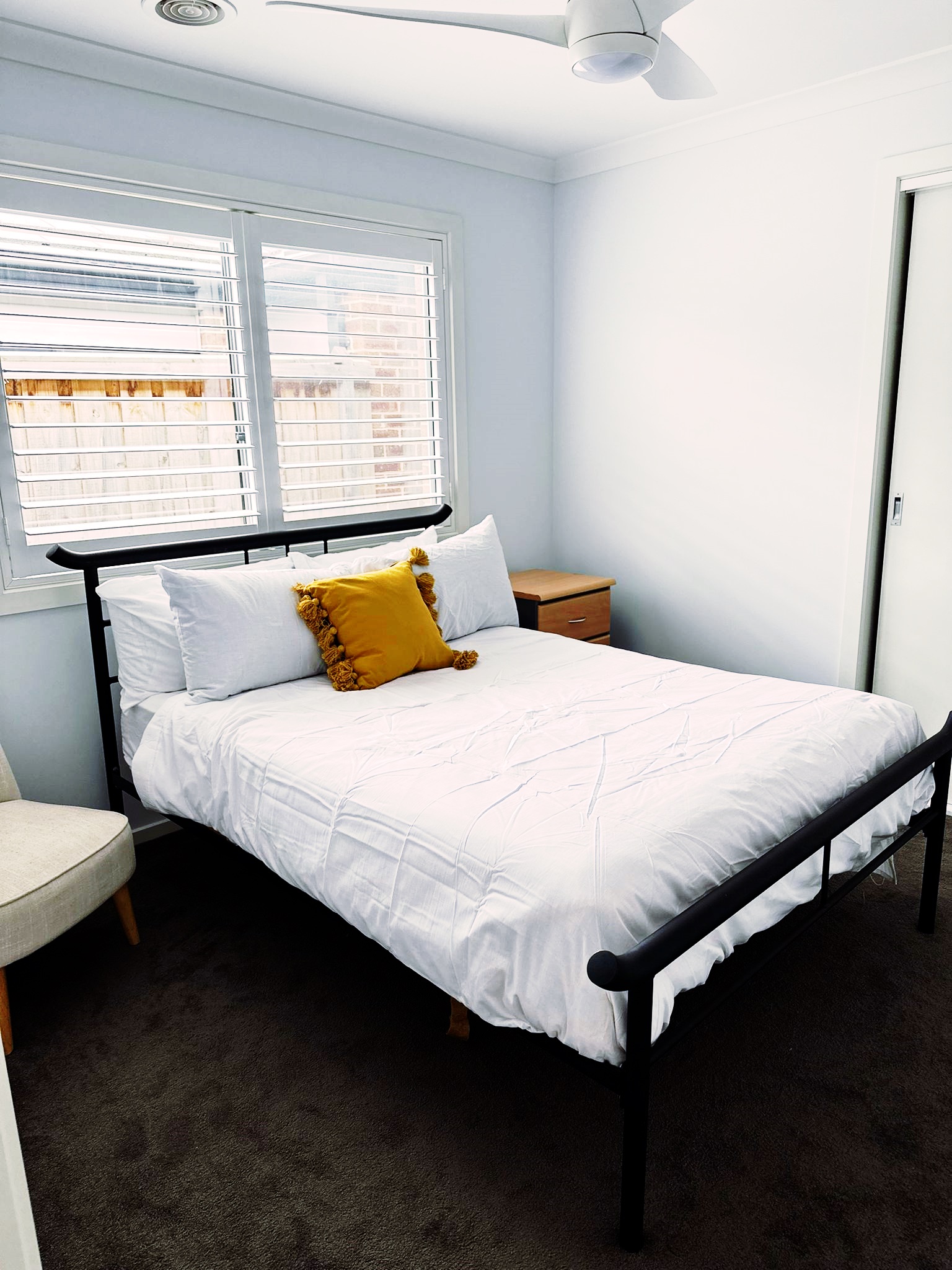 A picture of a bed in bedroom of an SIL house. The bed sheets are white and the bed frame is black