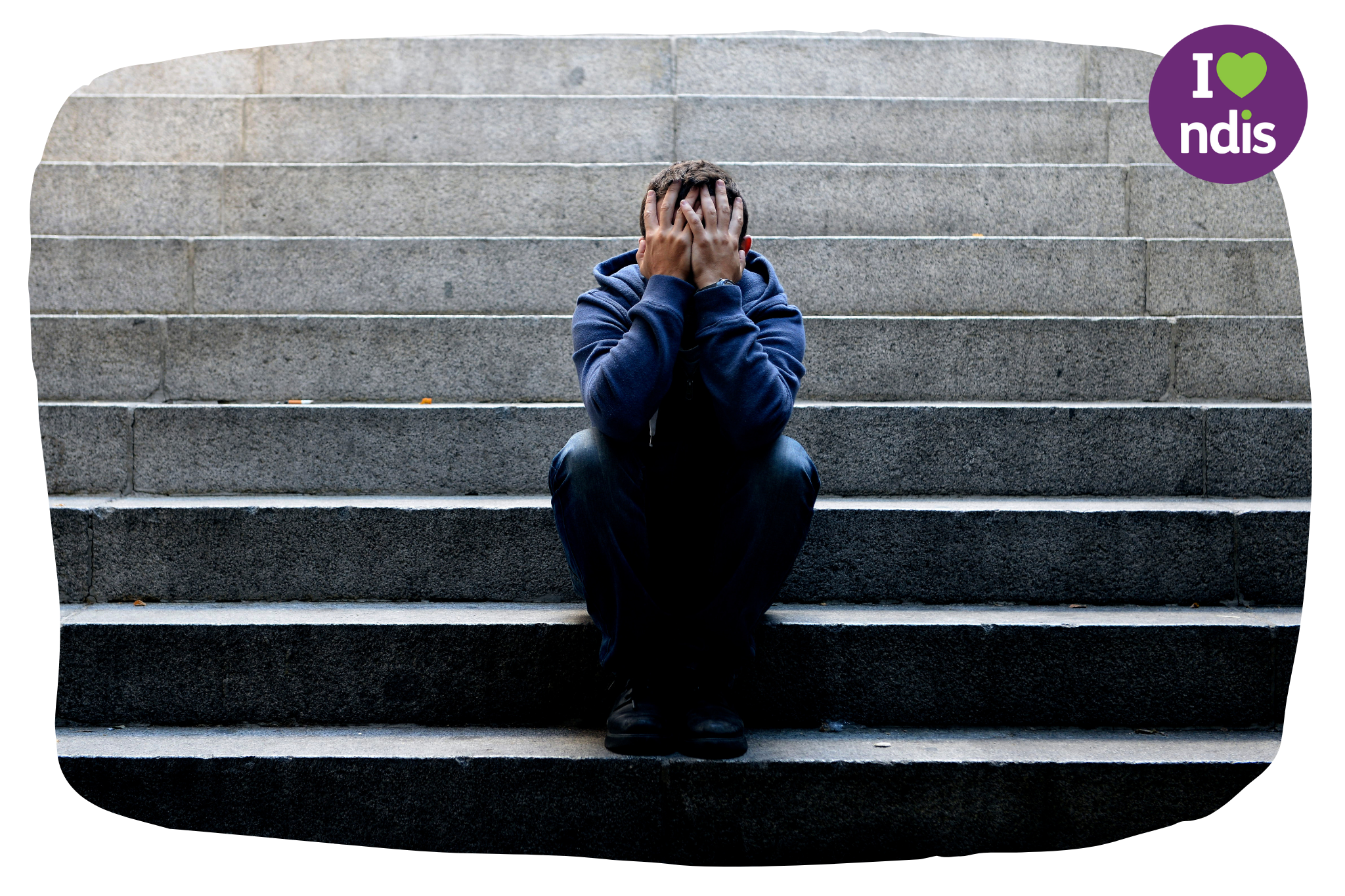 A man is sitting on a set of concrete steps with his head in his hands in distress.