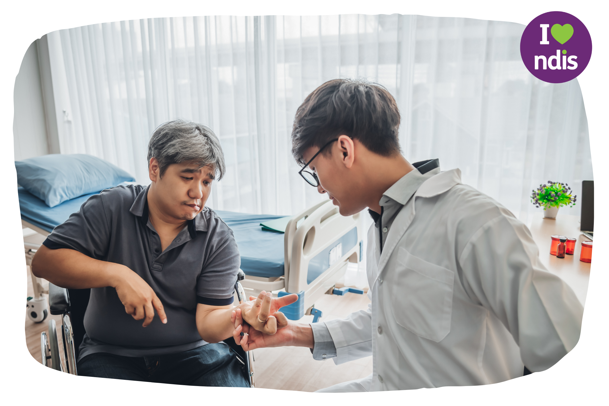 An asian doctor is in a hospital room holding the arm of a disabled person in a wheelchair. A hospital bed with blue sheets is visible in the background